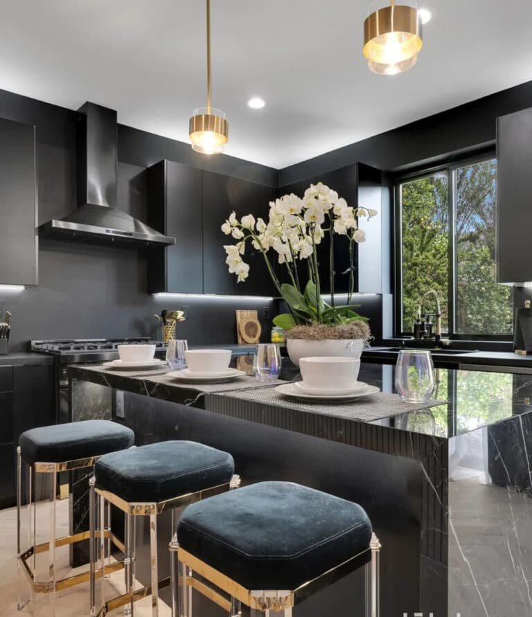 Modern kitchen featuring sleek black cabinetry, elegant pendant lighting, and a stylish island with plush stools, complemented by decorative orchids and table settings, showcasing high-quality remodeling by IAS Boutique Remodeling.