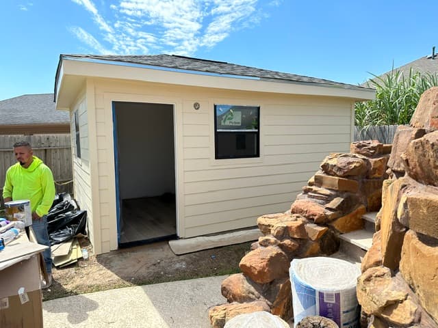 Newly built detached room addition with fiber-cement siding and a shingle roof in a Houston backyard.