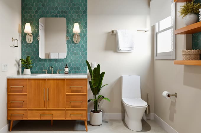 Remodeled bathroom with a teal patterned tile feature wall, wood vanity, and walk-in layout.
